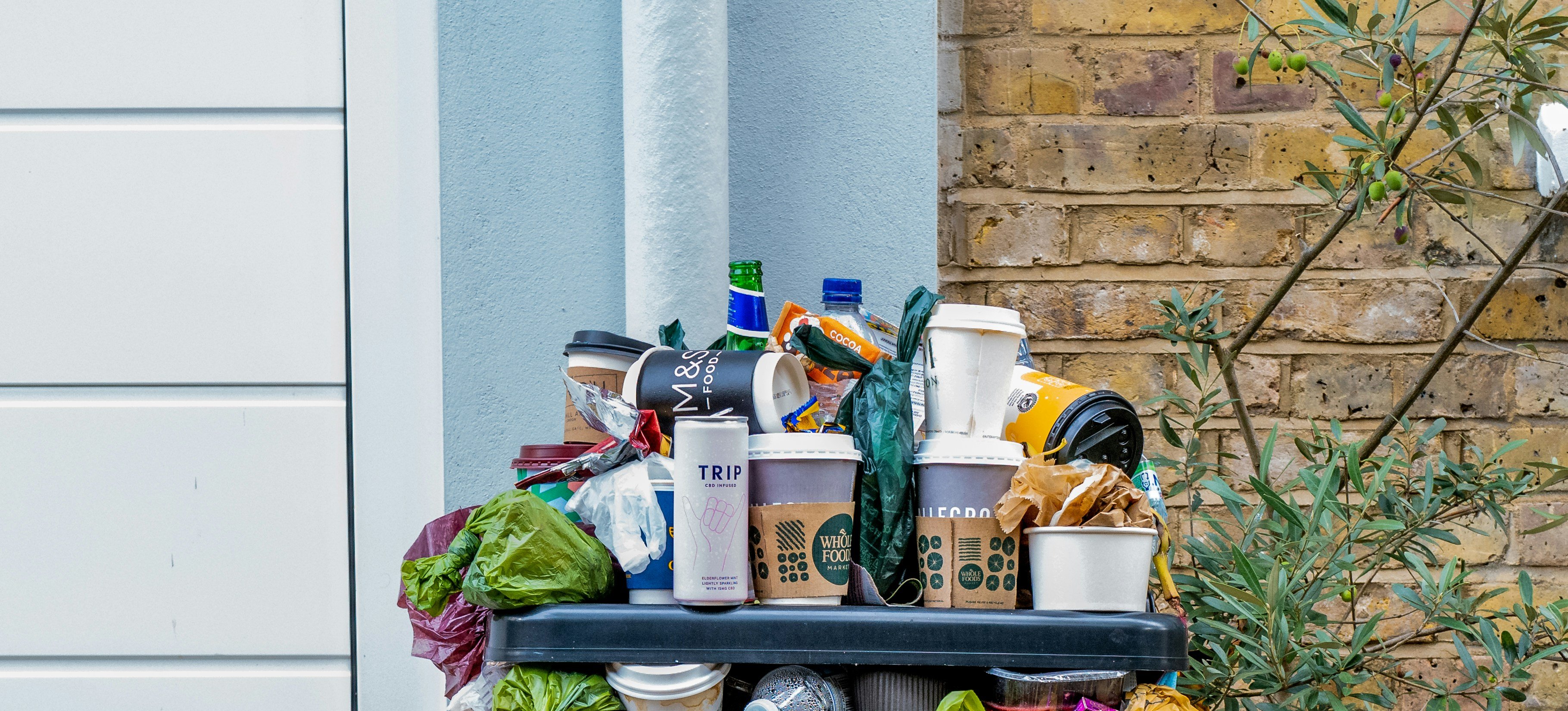 An overflowing outdoor trash bin, illustrating the least eco-friendly way to dispose of food waste