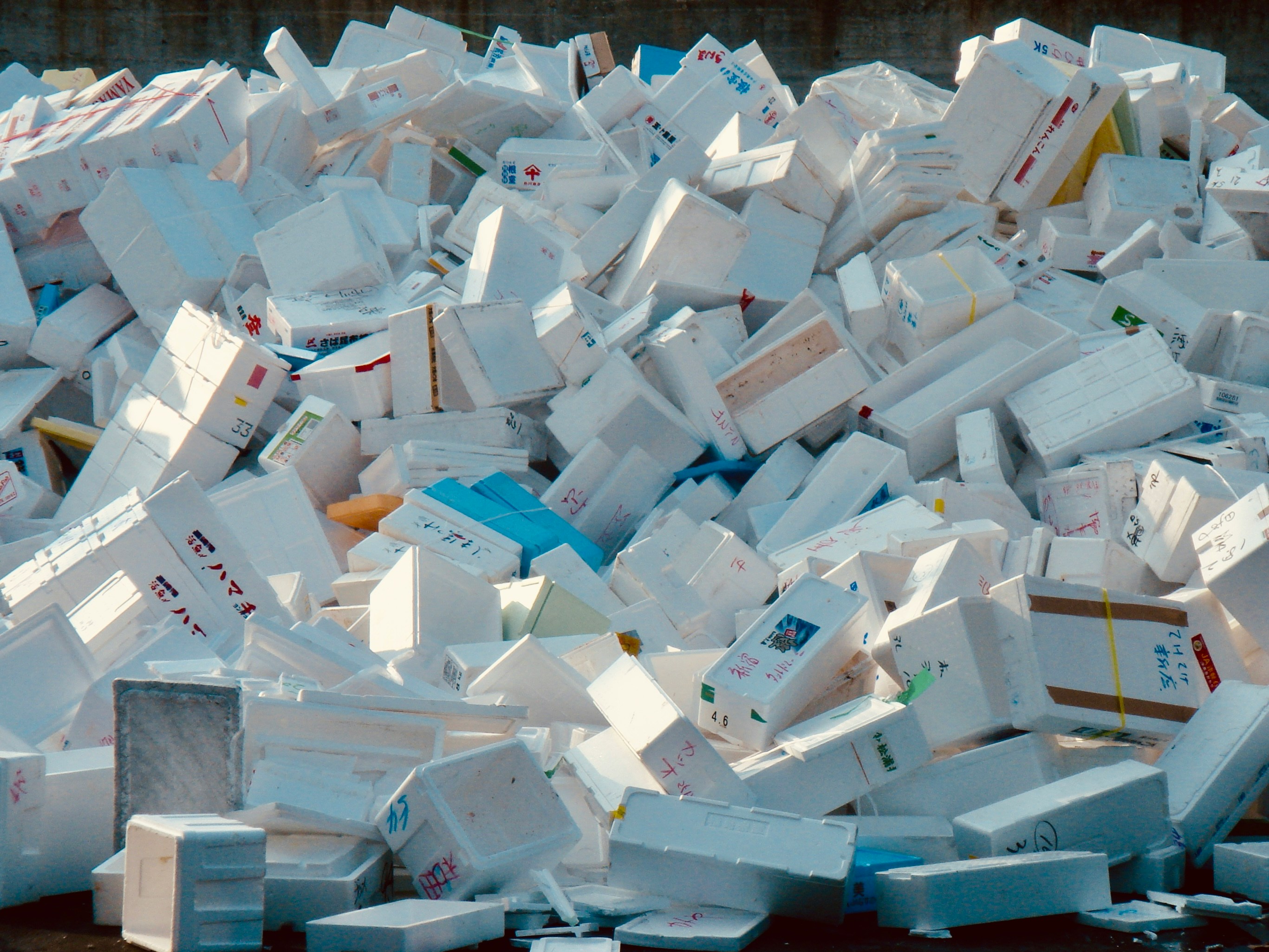 A pile of styrofoam packaging, plastic bags, and bubble wrap on a kitchen floor